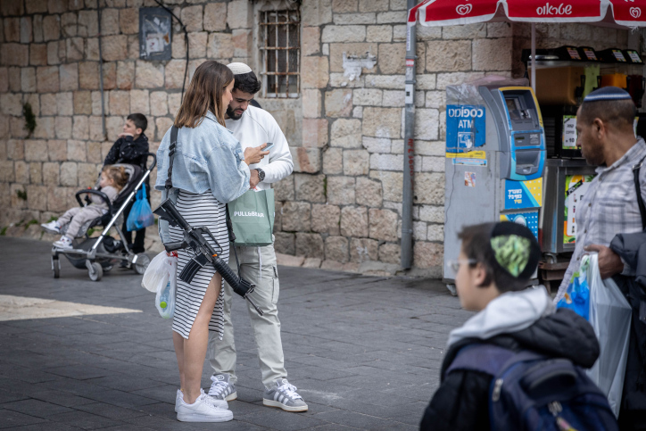 People walking with their rifles at the Mahane Yehuda Market in Jerusalem, February 23, 2024. Photo by Chaim Goldberg/Flash90